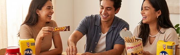 Three people sitting around a table with snacks and drinks, smiling and enjoying each other's company.